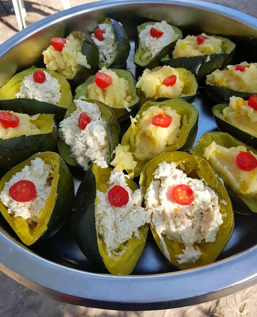 Dark green squash halves filled with shredded chicken mayo or mash, each topped with a cherry tomato